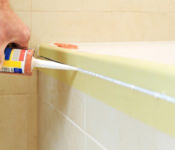worker-puts-silicone-sealant-caulk-joint-tub-wall_191163-2010